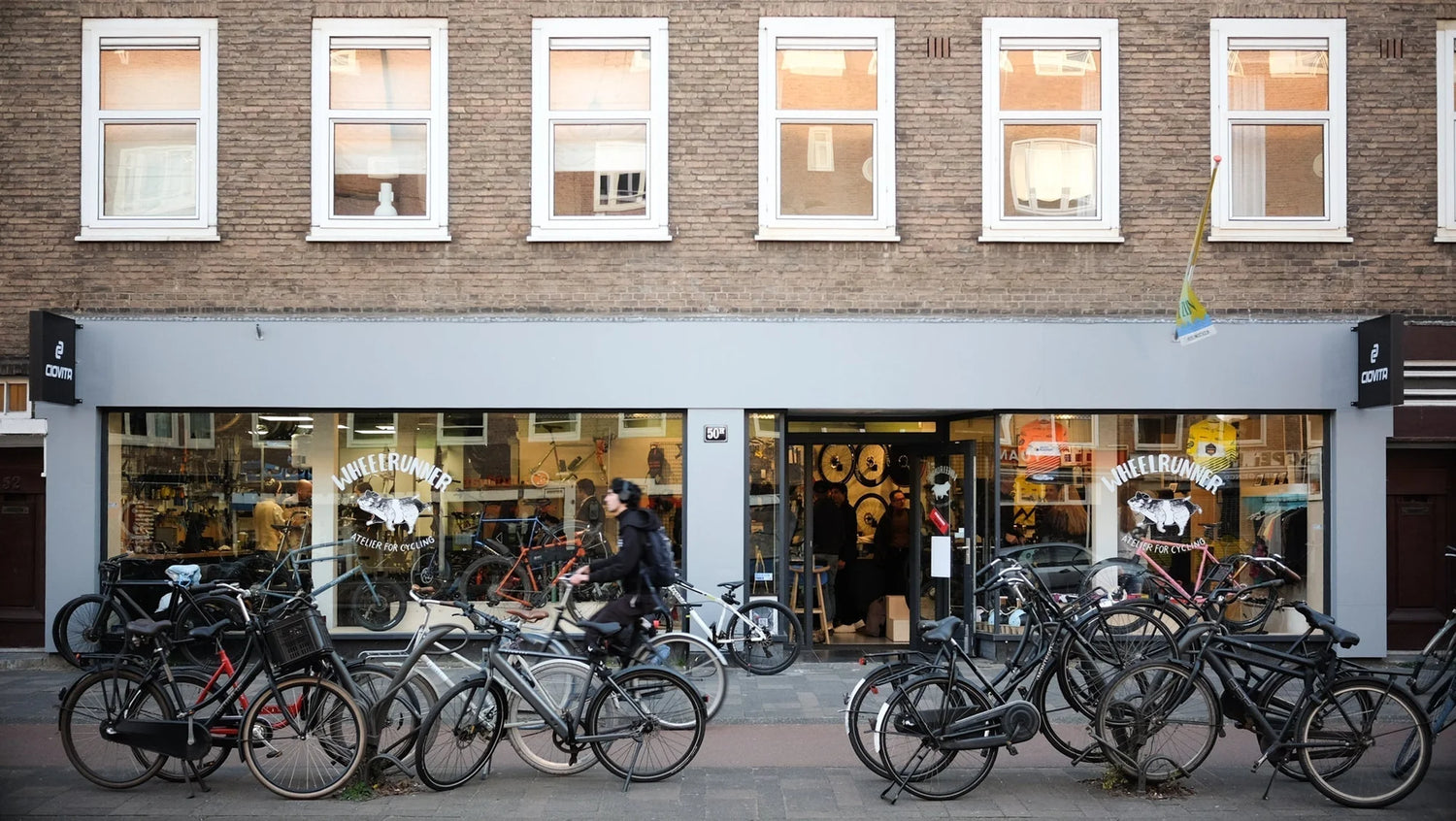 Bicycles parked outside a store with a brick facade and large windows.